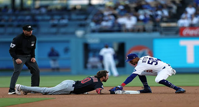 Dodgers fielder attempting tag on Cleveland Guardians runner sliding into base during MLB game
