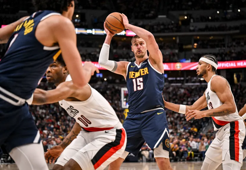 Nikola Jokić #15 of the Denver Nuggets holding the ball while surrounded by Portland Trail Blazers defenders at Ball Arena