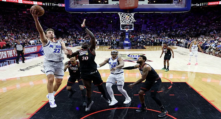 Orlando Magic forward Franz Wagner (#22) attempts a layup contested by Philadelphia 76ers center Andre Drummond (#30) during the 2026 NBA SoFi Play-In Tournament East game at Xfinity Mobile Arena, Philadelphia.