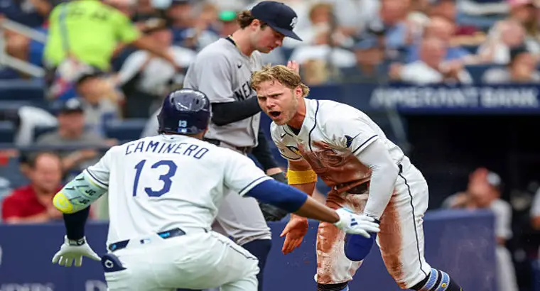 Tampa Bay Rays players Junior Caminero (#13) and a teammate celebrate a key play against the New York Yankees during their 2026 MLB game
