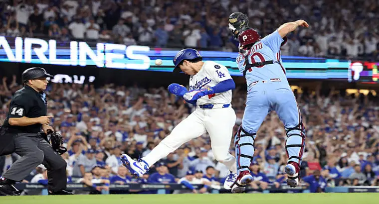 Philadelphia Phillies catcher J.T. Realmuto applies a tag at home plate against a Dodgers baserunner during the October 9, 2025 game at Dodger Stadium as the home plate umpire watches closely
